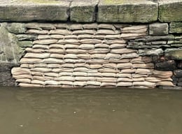 Where a bridge has collapsed from scour erosion, the void has been filled with concrete bagwork